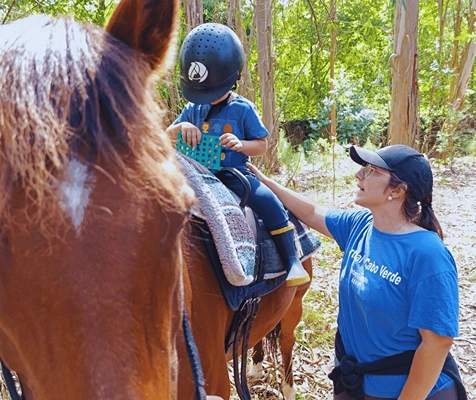 terapeuta com criança montada a cavalo