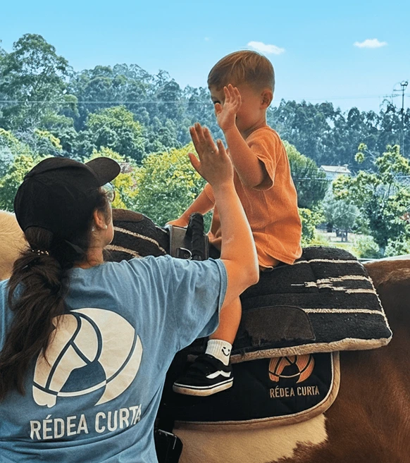 terapeuta com criança montada a cavalo